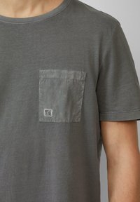 Grijze katoenen t-shirt met een textuur patch pocket. De pocket heeft een rechthoekige vorm en een klein logo in de onderhoek.
