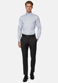 Camisa de cuello azul claro, con botones en la parte delantera y mangas largas. Se lleva con pantalones de vestir negros y zapatos de cuero negros. Diseño simple y ajustado.