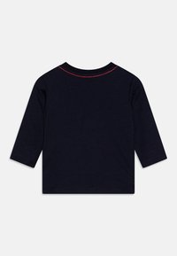Navy blue long-sleeve shirt with red stitching at the neckline. Soft cotton material, straight cut, and rounded hem. No patterns or graphics.