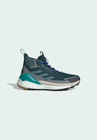 Dunkelgrüne Sportschuhe mit einem unterstützenden hohen Design, strukturiertem Mesh-Obermaterial, lila Schnürsenkeln und weißer Zwischensohle mit schwarzem Gummiausgang.