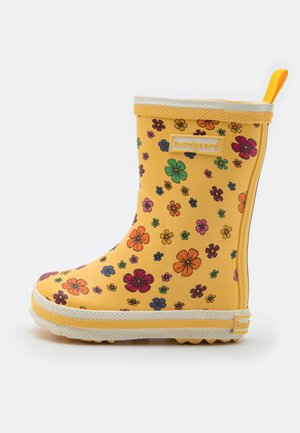 Botte de pluie en caoutchouc jaune avec des motifs floraux colorés et une languette à l'arrière, montrée de profil sur fond blanc.