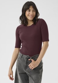 Burgundy ribbed top with a crew neck and short sleeves, paired with high-waisted gray jeans featuring front pockets and a button closure.