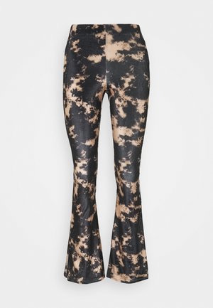 Pantalones acampanados hechos de un material elástico con un patrón de tie-dye en negro y beige. Presentan una cintura alta y un ajuste estrecho en las caderas.
