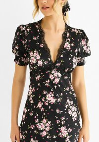 Black floral dress featuring short puff sleeves, a deep V-neck with lace trim, and a fitted silhouette adorned with pink and green flower patterns.