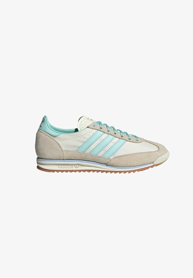 Sneakers gri deschis din suede cu accente turcoaz. Prezintă trei dungi orizontale, şireturi plate şi o talpă din cauciuc texturată.