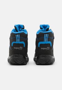 Scarpe high-top nere e blu con suole testurizzate, dotate di una morbida fodera blu e cuciture a contrasto. Il nome del marchio 'superfit' è visibile sul retro.