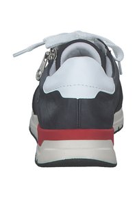 Sneaker in pelle nera con linguetta e lacci bianchi, accentuazione rossa sulla suola intermedia e chiusura con zip sul retro. Superficie texturizzata.