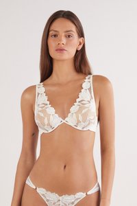 Soutien-gorge en dentelle avec motif floral, décollet�é en V profond, bords scallopés et bretelles ajustables. La couleur est blanc cassé avec des sections transparentes.