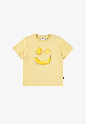 Dzeltena kokvilnas T-kreklu ar attēlu, kurā redzama banana un citrona šķēlītes, kas drukātas centrā. Ar apaļu kakla izgriezumu un īsām piedurknēm.