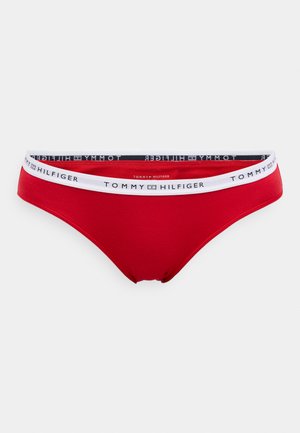 Sarkans bikini apakšda ar baltu jostu, kas rotāta ar melno "TOMMY HILFIGER" logo. Izgatavota no gludas un elastīgas platmateriala.