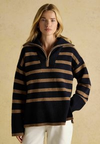 Dunkelblaue und sandfarbene gestreifte Pullover mit Reißverschlusskragen, geripptem Textur und einem lockeren Schnitt mit seitlichen Schlitzen.
