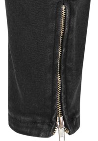 Czarne dżinsowe spodnie z wyraźnym złotym zamkiem błyskawicznym wzdłuż zewnętrznego szwu. Posiadają prosty krój i gładką fakturę.