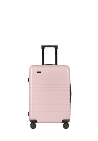 Pink hard-shell suitcase with a smooth surface, horizontal grooves, black wheels, and a retractable handle. Lightweight and durable design.