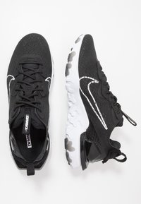 Black athletic shoes with a breathable mesh upper, white detailing, and a textured white sole. Features a logo and padded collar for support.