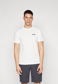 Tricou alb din bumbac, cu mâneci scurte, guler rotund și un mic patch cu logo maro pe piept. Purtați cu pantaloni scurți închisi la culoare.