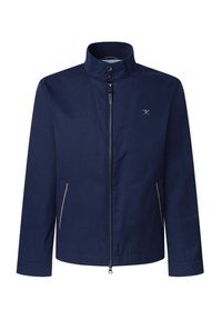 Chaqueta azul marino con cuello alto, cierre frontal y dos bolsillos laterales con acentos de color claro. Textura de tela suave y mate.