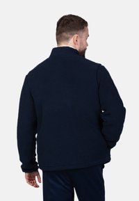 Navyblaue Fleecejacke mit hohem Kragen, strukturiertem Obermaterial und langen Ärmeln. Bietet eine lockere Passform ohne sichtbare Beschläge.