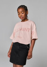 Palyti rožinė per didelė marškinė su užrašu "ALLSAINTS" ir "LONDON" tamsesne rožine spalva, derinama su juoda džinsine sijonu, puoštu kniedėmis.