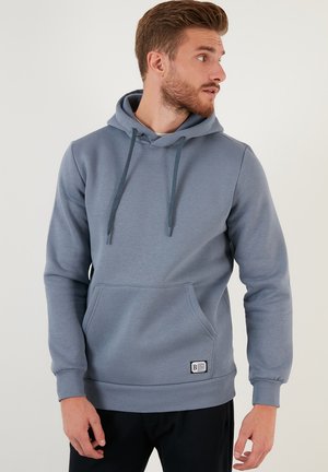 Grey hoodie with a front pocket, adjustable drawstring hood, ribbed cuffs, and hem, made from a soft, smooth material. Features logo patch.