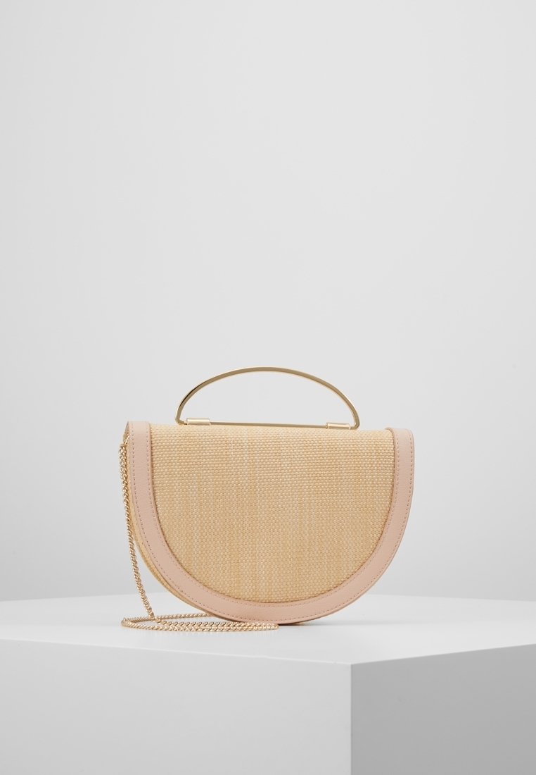 Torebka w kształcie półksiężyca, pleciona w kolorze beżowym z jasnoróżowymi wykończeniami, złotą rączką oraz złotym łańcuszkiem na białym piedestale.