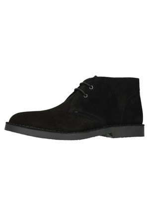 Zwarte suède enkelschoenen met een gladde textuur, voorzien van twee oogjes voor veters en een platte rubberen zool. Minimalistisch ontwerp met een ronde neus.