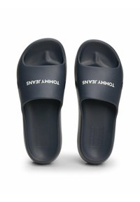 Chanclas de color azul marino fabricadas en plástico suave con el logotipo blanco "TOMMY JEANS" en la correa. Diseño destalonado, plantilla contorneada para mayor comodidad.