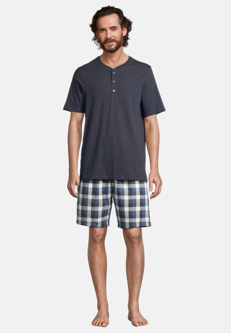 Maglietta henley grigio scuro a maniche corte con tre bottoni, abbinata a pantaloni corti a quadri blu e bianchi. Vestibilità comoda, adatta per il relax.