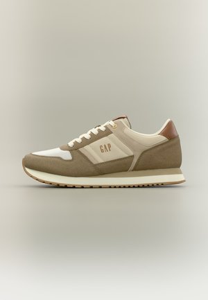 Hellbrauner und beiger Sneaker in lässigem Stil mit weißen Schnürsenkeln, Gummisohle und "GAP"-Logo auf der Seitenfläche, vor einem schlichten Hintergrund.