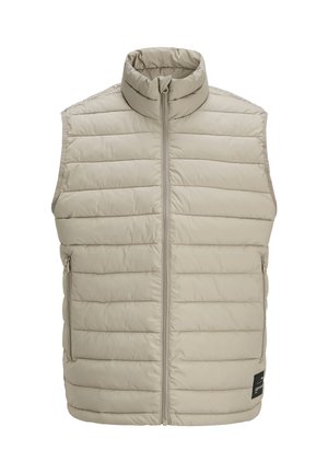 Chaleco sin mangas acolchado beige con cuello alto, cremallera delantera, dos bolsillos laterales con cremallera y etiqueta negra rectangular en la parte inferior delantera.