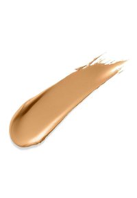 Creamy, liquid foundation swatch in a warm, medium beige tone with a smooth texture and glossy finish, applied in a tapered line.