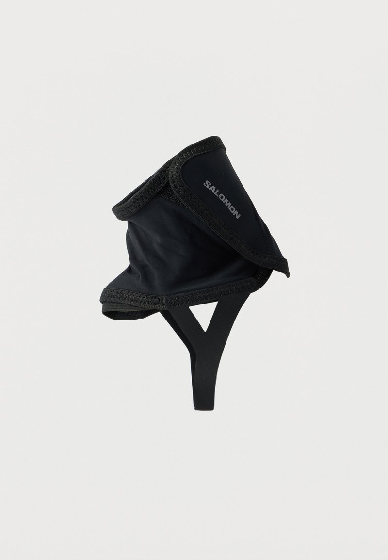 Μαύρος επεκτατήρας Salomon με ρυθμιζόμενο ιμάντα με γάντζο και βρόχο και ελαστική υποστήριξη κάτω από το πόδι σε λευκό φόντο.