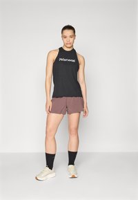 Svart ermeløs tanktop med "Normal"-logo, kombinert med burgunder shorts. Brukt med lette joggesko og svarte sokker. Nøytral bakgrunn.