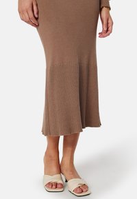 Robe midi en tricot côtelé marron clair avec ourlet évasé et sandales crème à enfiler avec larges brides et un petit talon. La texture est lisse et extensible.