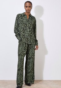 Green and black striped blouse and wide-leg pants set, featuring a button-up design, soft fabric, and relaxed fit with a smooth texture.