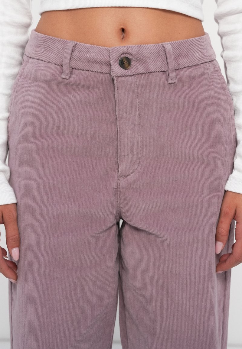 Pantalones de pana lila de cintura alta, con costillas verticales, cierre de botón y bolsillos laterales. Tejido texturizado con un acabado suave.