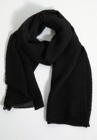 Bufanda negra hecha de tela con relieve, que presenta una superficie texturizada y bordes irregulares. El material parece ligero y flexible.