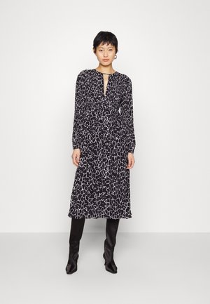 Μαύρο και άσπρο φόρεμα με σχέδιο ζώου, μακριά μανίκια, βαθύ ντεκολτέ, τονισμένη μέση και φουσκωτό φουστάνι. Φοριέται με κομψά μαύρα μποτάκια.