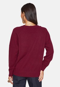 Maglione a maglia color bordeaux con una vestibilità morbida, maniche raglan e polsini a coste. Presenta una texture semplice e morbida con scollatura rotonda.