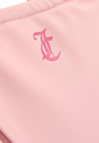 Tissu de maillot de bain rose présentant une texture lisse et un logo en cursive en relief d'une teinte rose légèrement plus foncée. Aucun autre détail visible.