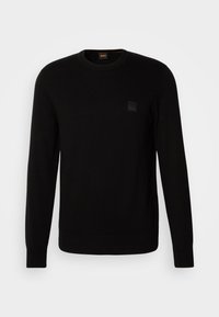 Zwarte gebreide trui met lange mouwen, ronde hals en een klein gewafeld logo-opdruk op de borst. Voelt glad aan aan de hele trui.
