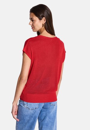 Pull rouge à manches courtes avec une coupe décontractée, tricot texturé et ourlet côtelé. Associé à un jean bleu clair avec un design classique de poche.
