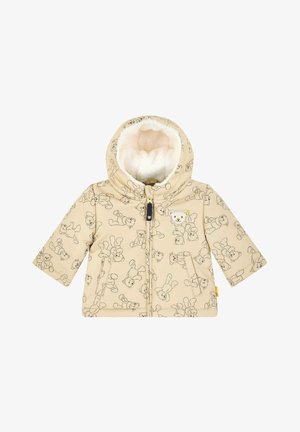 Doudoune beige avec un motif ours en peluche, fermeture éclair et capuche doublée en peluche. Elle dispose de deux poches avant et de poignets ajustables.