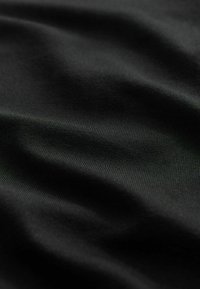 Černá tkanina s hladkým, mírně texturovaným povrchem, s jemnými vlnami a záhyby, které zdůrazňují její lehké a pružné vlastnosti.