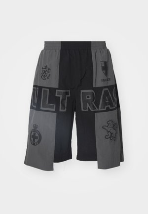 Shorts noirs et gris avec un waistband élastique, comportant divers graphismes et motifs, y compris du texte et des emblèmes, dans une coupe décontractée.