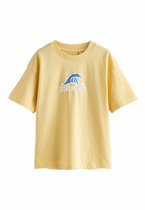 Gul T-shirt med korte ærmer med en blå bølgegrafik og teksten "CATCH SOME WAVES" trykt på frontens midte.