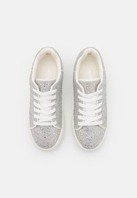 Silver sneakers with shimmering rhinestones, white laces, and a structured design. Smooth texture and rounded toe. Minimal white accents.