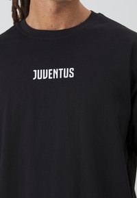 Black cotton t-shirt featuring the word "JUVENTUS" in bold white letters on the chest. Simple design with a crew neckline.