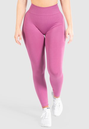 Hoge taille roze leggings gemaakt van rekbaar materiaal, met een gladde textuur en een strakke pasvorm, gecombineerd met witte sportschoenen.