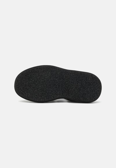 Semelle de chaussure noire en caoutchouc avec une surface texturée et des bords arrondis, présentant un rebord extérieur lisse et un motif de grip antidérapant.