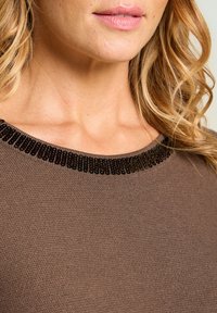Haut en tricot marron avec un large décolleté, orné d'un accent décoratif de perles noires autour du col. Texture lisse et coupe ajustée.